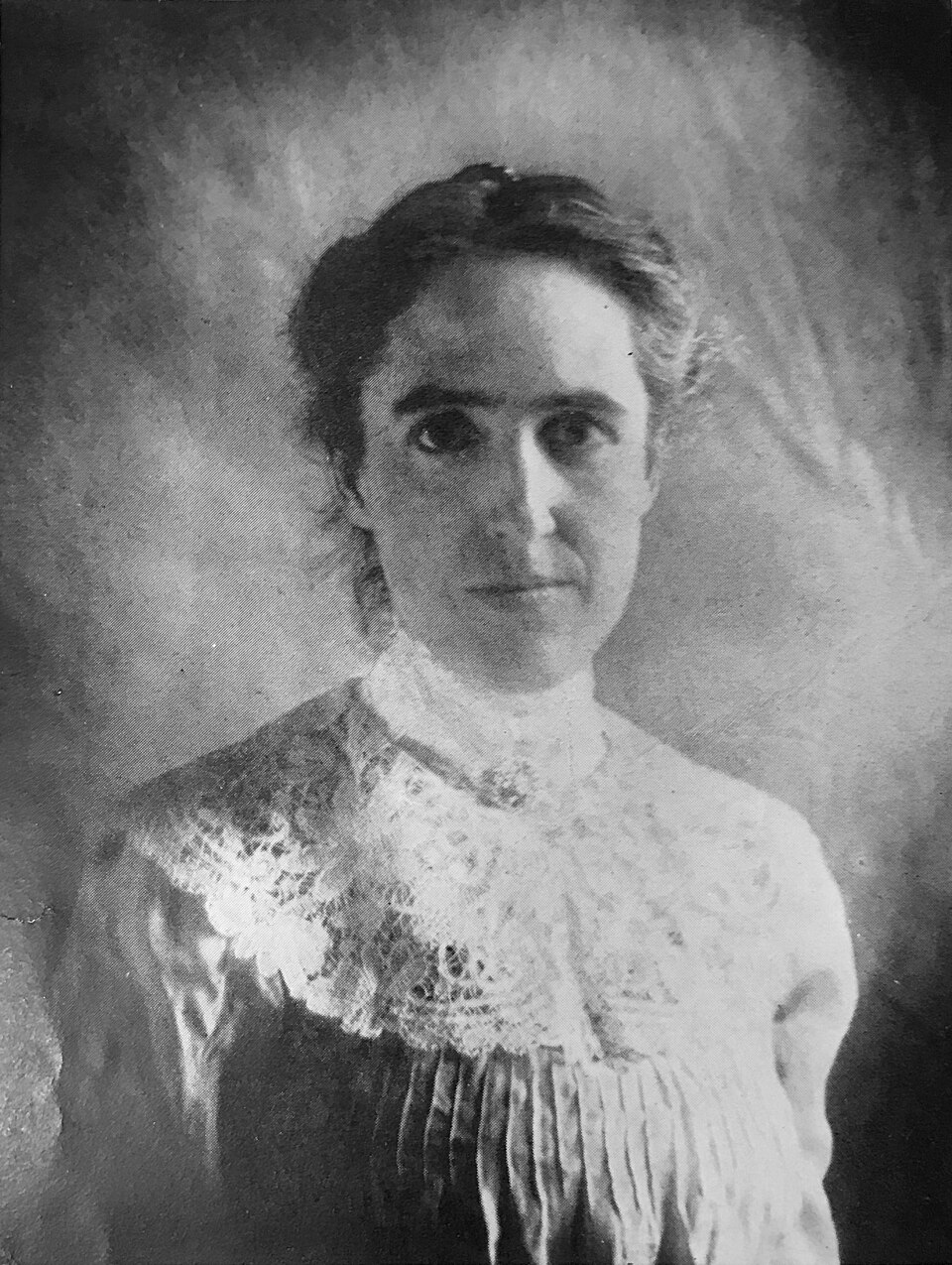 Black and white portrait of Henrietta Swan Leavitt in a white lace high-collared blouse, looking directly at the camera.